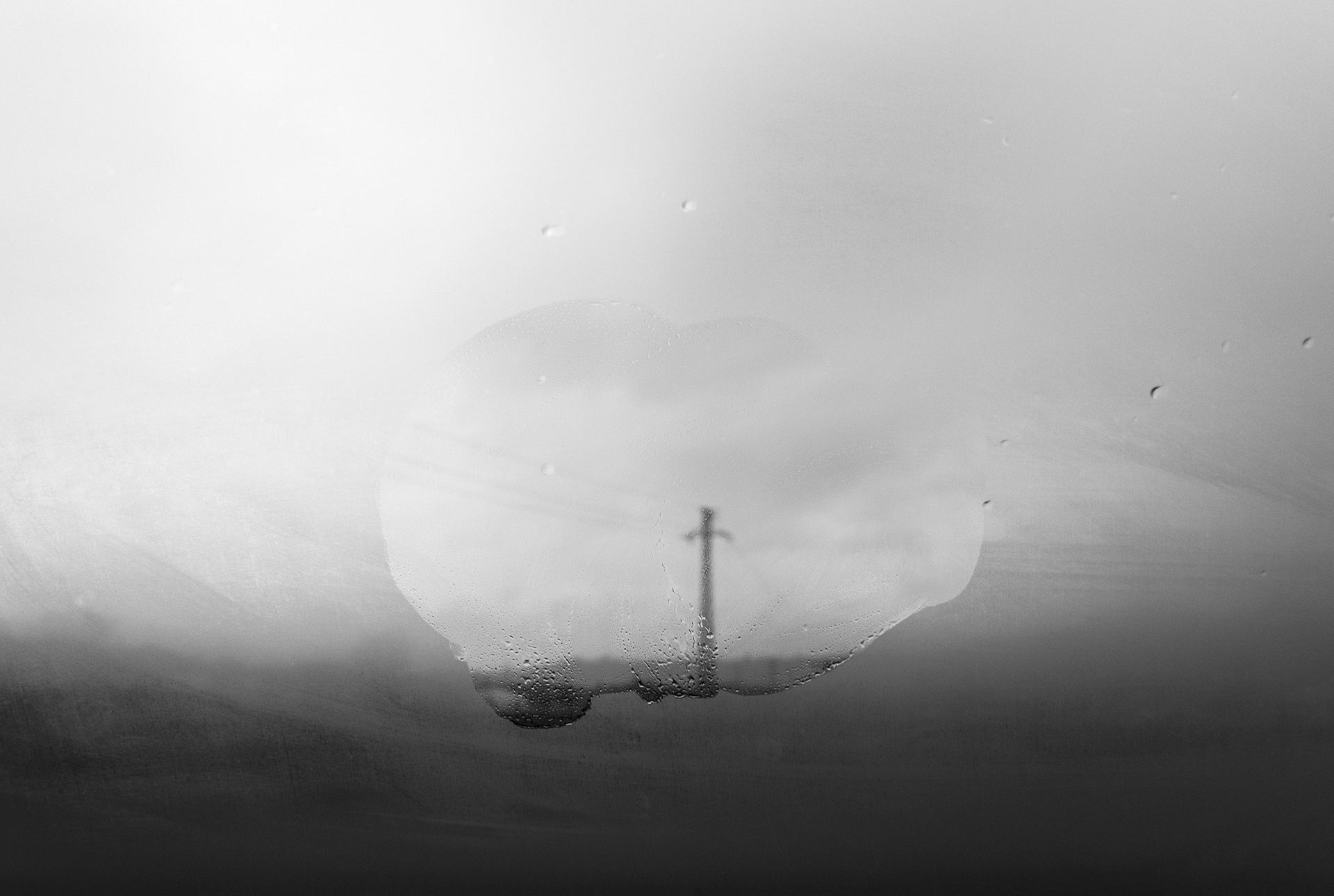 Cristal empañado con una zona limpia y un poste desenfocado al fondo